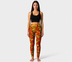 Woman wearing a black sports bra and colorful leaf-patterned leggings on a white background