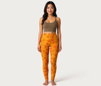 Woman wearing a brown sports bra and orange leggings with leaf pattern on a white background
