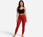 Woman wearing red patterned maple leaves leggings and black crop top on a white background